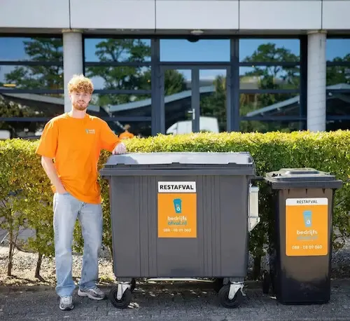 Medewerker www.bedrijfsafval.nl naast een 1700 liter restafval container